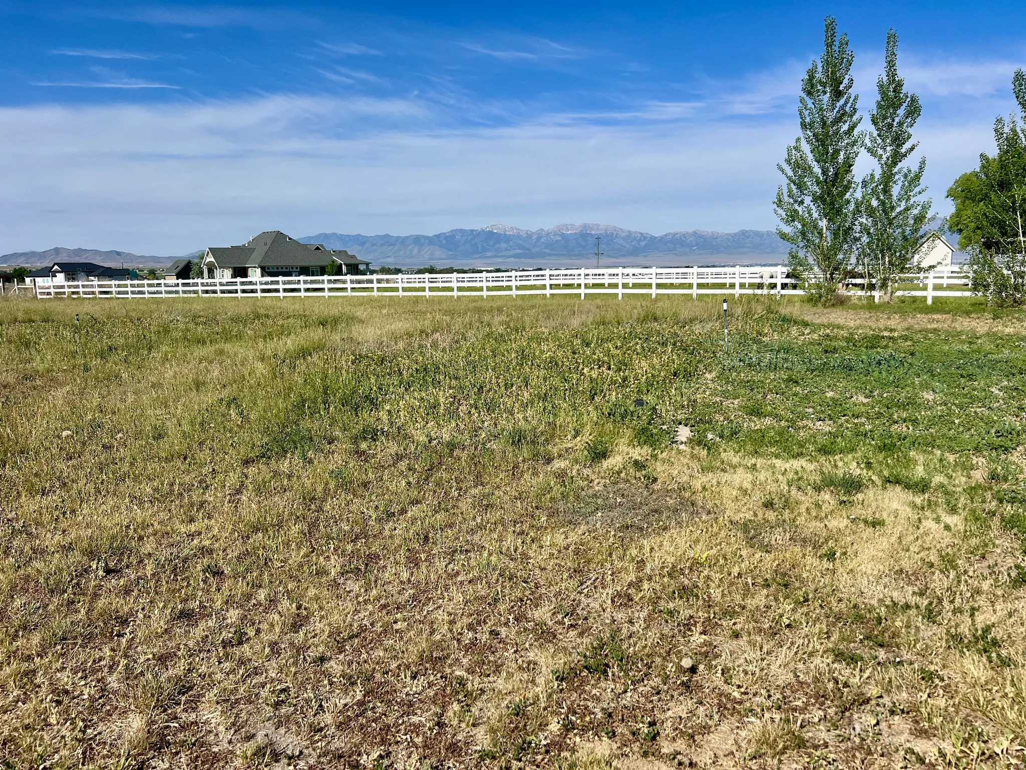 Expansive open land featuring a white fence line and distant mountain range