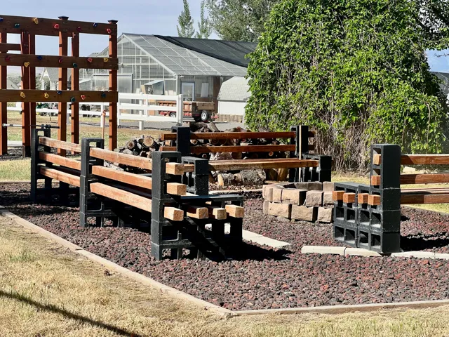 Outdoor gathering space featuring a stone-lined fire pit, surrounded by wood and concrete block benches