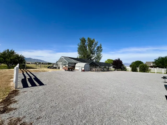 Expansive gravel lot featuring a large greenhouse structure with a clear roof and dark siding