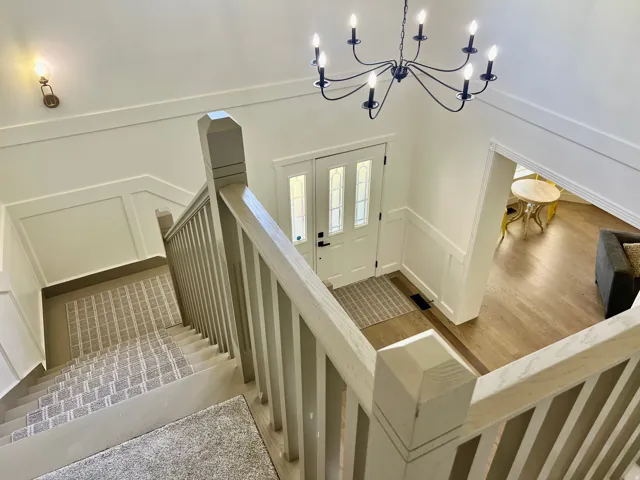 Entry foyer featuring a white paneled door with glass inserts, a black chandelier, and light wood-finish flooring
