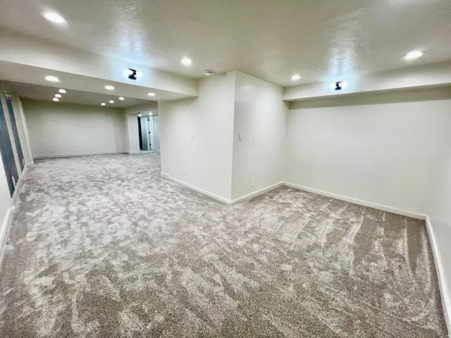 Spacious room featuring new carpeting, recessed lighting, white baseboards, and neutral wall finishes