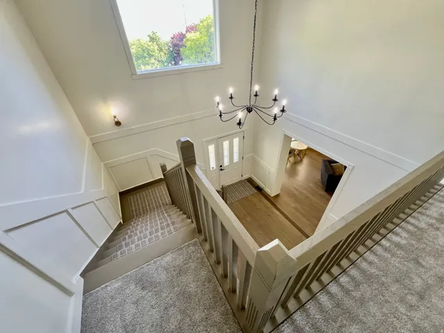 Two-story entryway featuring a black chandelier and wood-finish flooring with a contrasting inlay