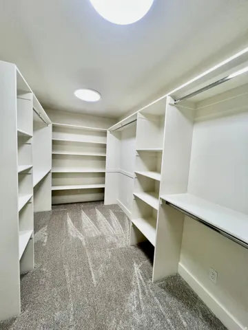 Walk-in closet featuring extensive built-in shelving, hanging rods, and recessed lighting