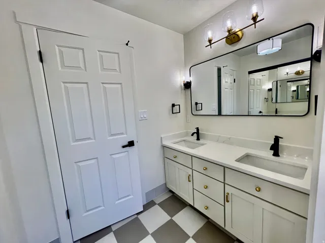 Double vanity featuring white cabinetry with gold-tone hardware, quartz countertops, and integrated rectangular sinks