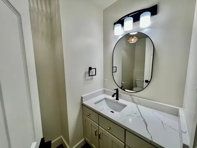 Modern vanity with a white rectangular undermount sink, a stone-finish countertop, and a matte black faucet