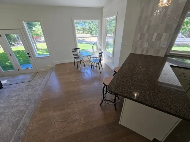Kitchen island with a dark granite countertop, light-toned cabinetry, and a patterned tile backsplash