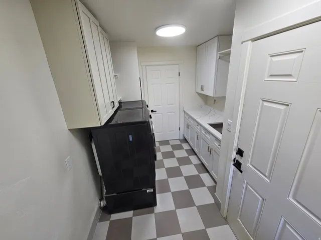Utility room featuring checkerboard flooring, white cabinetry, a built-in sink, and white paneled doors