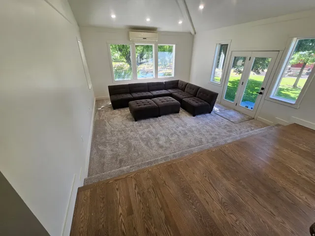 Sunlit living space featuring a vaulted ceiling with recessed lighting
