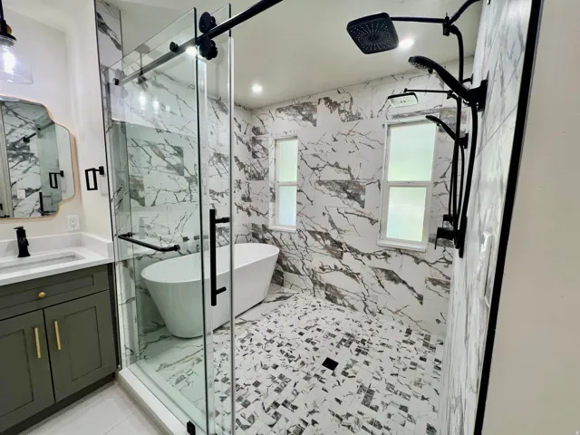 Expansive walk-in shower featuring a freestanding tub, floor-to-ceiling marble-look tile, and a multi-function matte black shower system