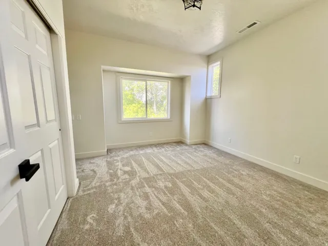 Bright room featuring two windows, neutral-toned carpet, and white trim