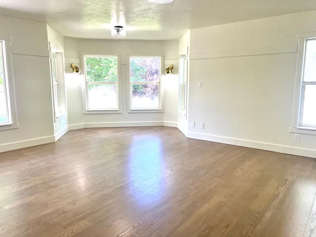 Spacious room featuring wood-finish flooring, white trim, and multiple windows