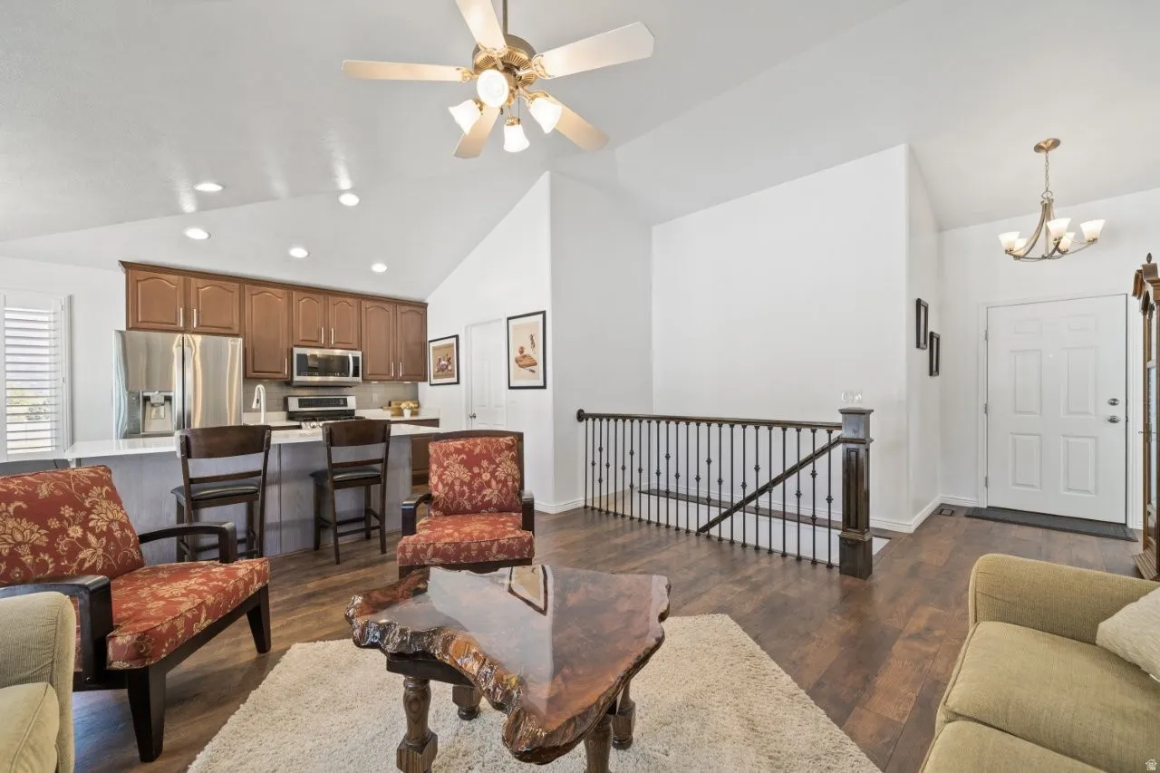 Living room with dark wood-style floors, recessed lighting, a chandelier, high vaulted ceiling, and ceiling fan
