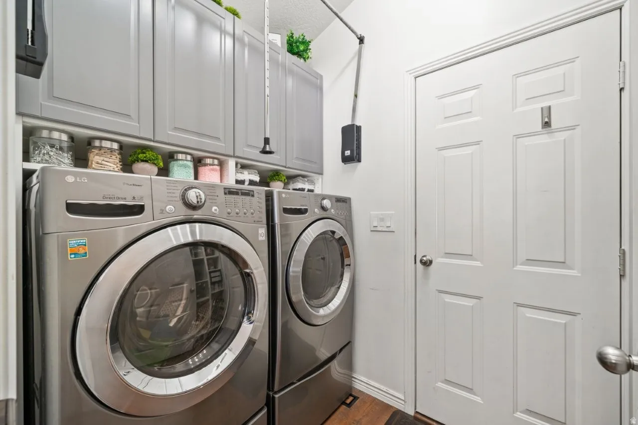 Laundry room featuring washer and clothes dryer, cabinet space, and dark wood-type flooring