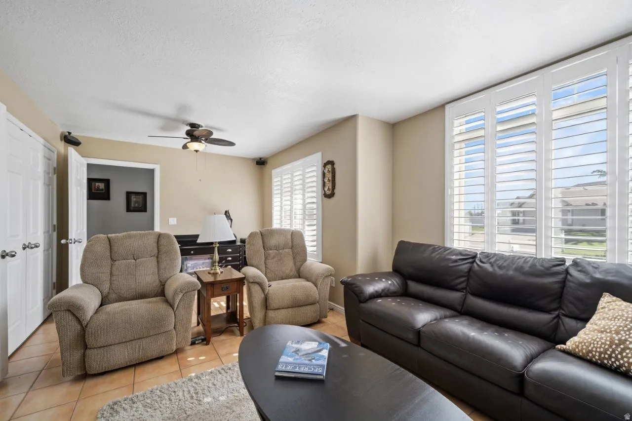 Living room featuring tile patterned floors, a ceiling fan, and a textured ceiling