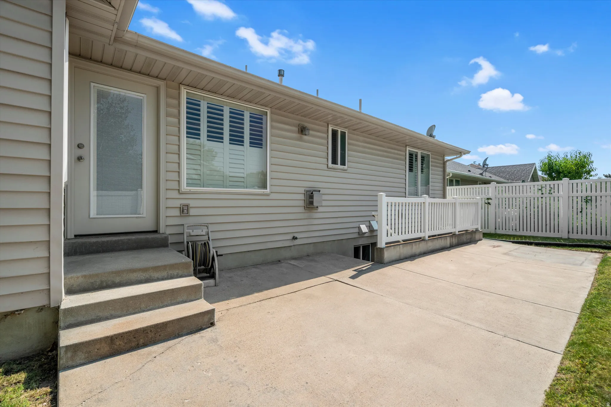 Exterior patio featuring a concrete surface, white picket fencing, and siding