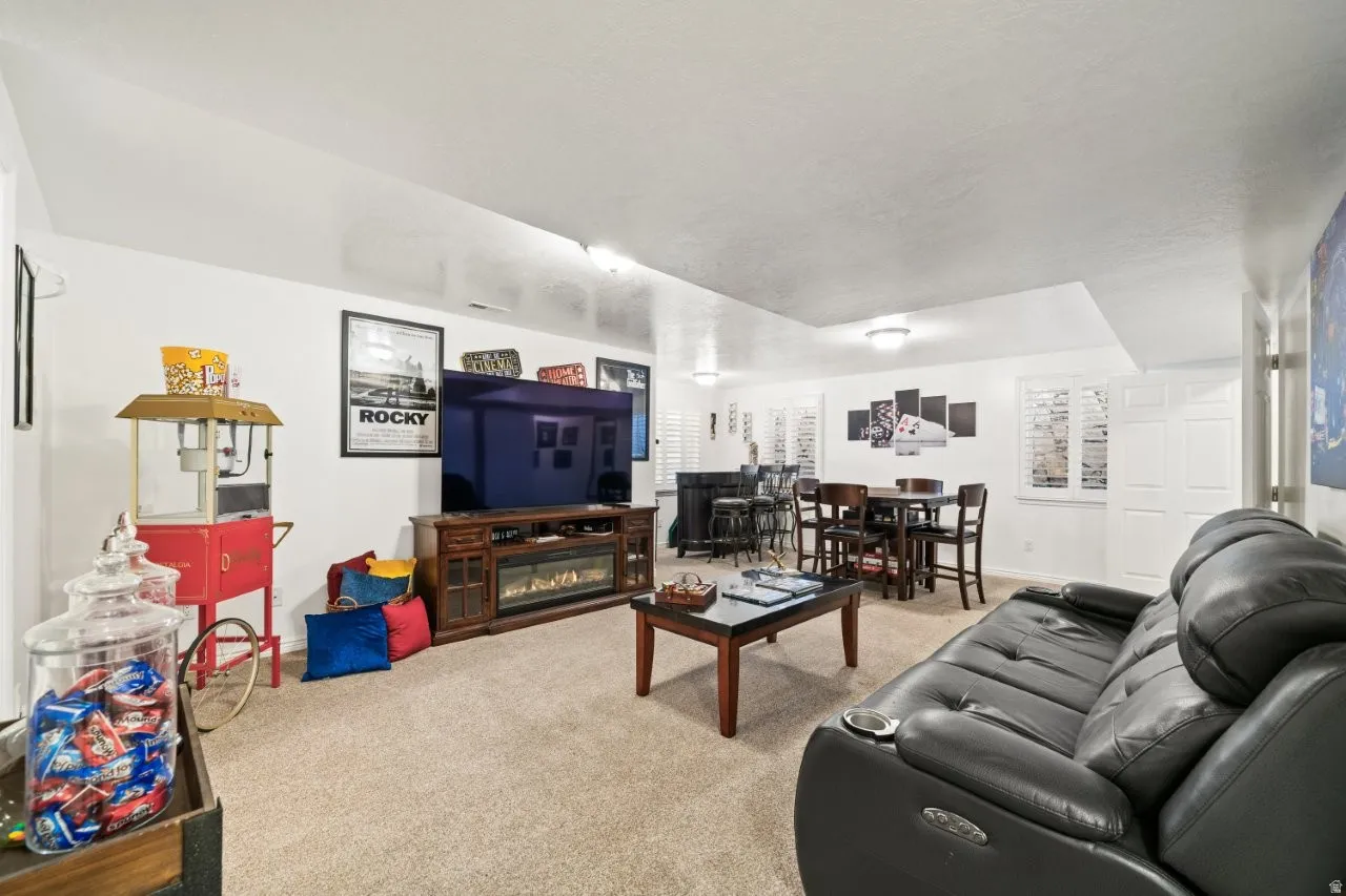 Carpeted living room with a glass covered fireplace and baseboards