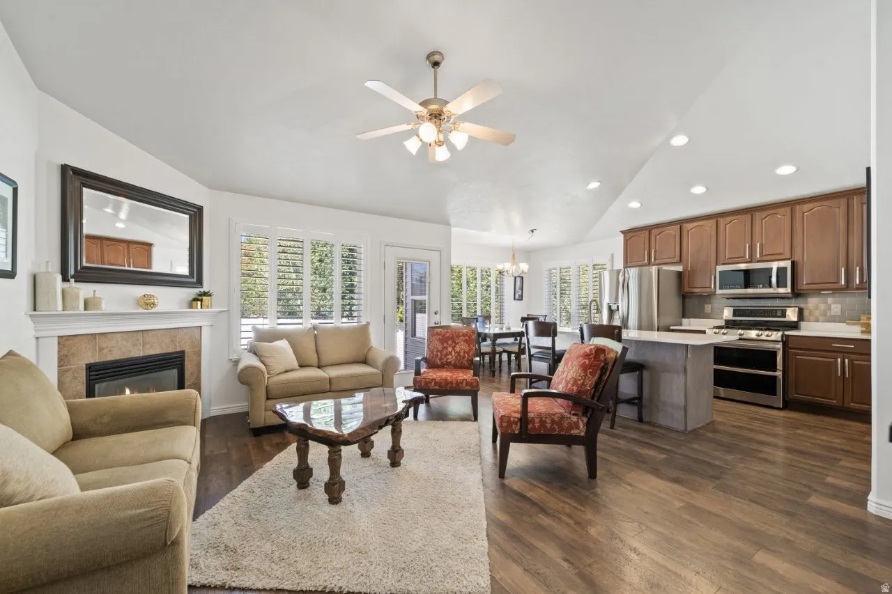 Living room featuring lofted ceiling, a chandelier, dark wood-type flooring, recessed lighting, and healthy amount of natural light