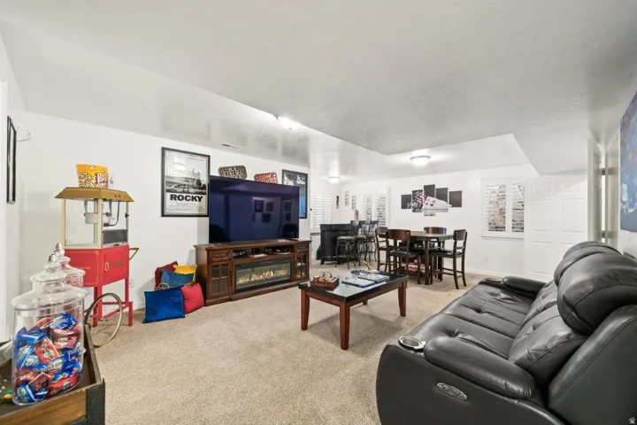 Carpeted living room with a glass covered fireplace and baseboards