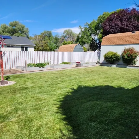 Expansive lawn with a white privacy fence, raised garden beds,