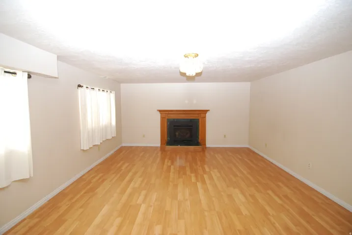 Spacious interior featuring wood-finish flooring, a decorative fireplace with a wood mantle, and an overhead lighting fixture