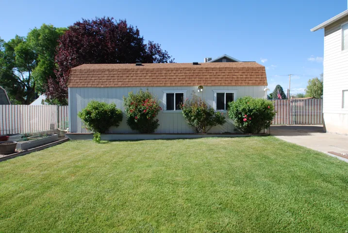 Expansive green lawn with a white privacy fence. 12x32 shed/workshop