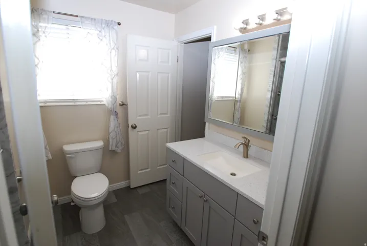 Bathroom featuring a gray vanity with a white countertop, an integrated sink, and a brushed gold-tone faucet