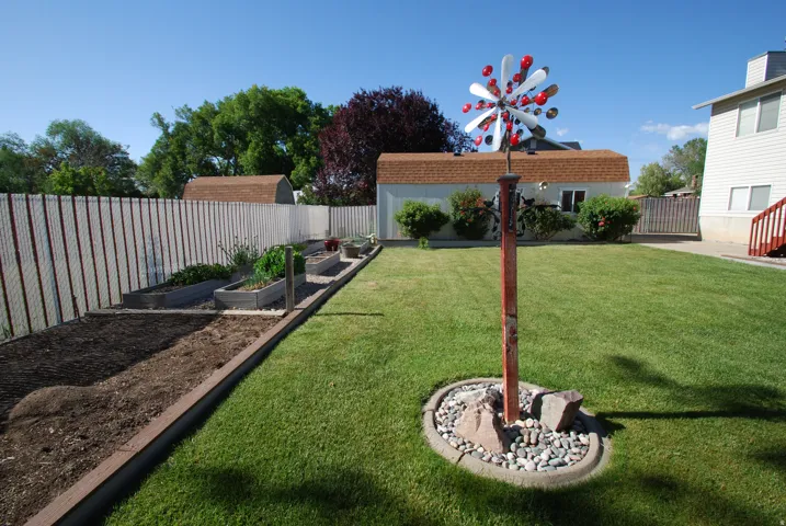Expansive backyard featuring a lush lawn, raised garden beds, and a chain-link fence with privacy slats