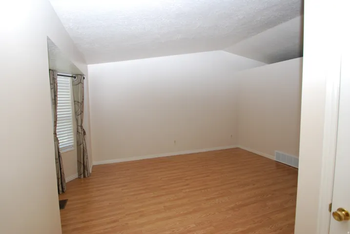 Spacious interior room featuring wood-finish flooring, neutral wall paint, and a textured ceiling