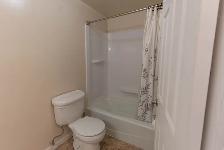 Bathroom featuring a white toilet and a tub/shower combination with a white surround
