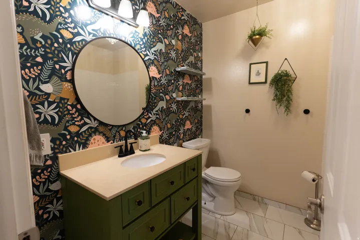 Main floor bathroom, with whimsical wall paper! Love the round mirror !