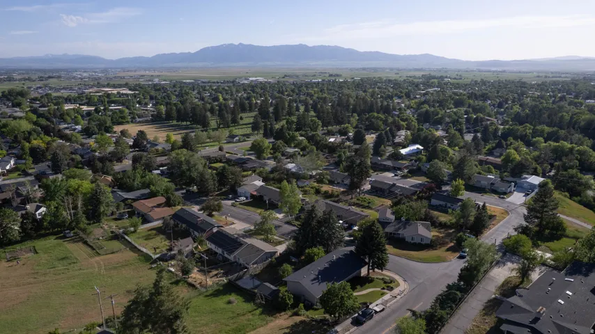 Expansive neighborhood setting featuring a mix of residential properties, mature trees, and mountainous terrain in the distance