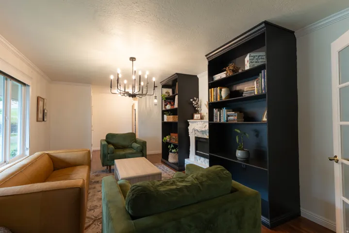 Living area featuring rich wood-finish flooring and crown molding. Shelving stays !