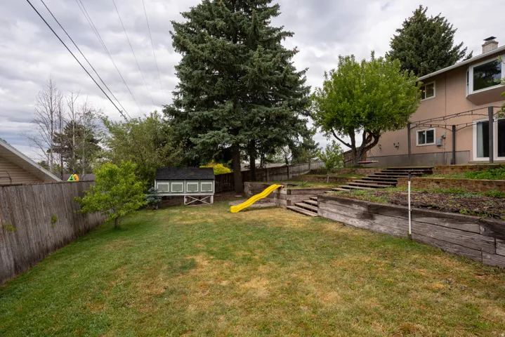 Fully fenced back yard, mature trees, garden spot, slide, and fun spot