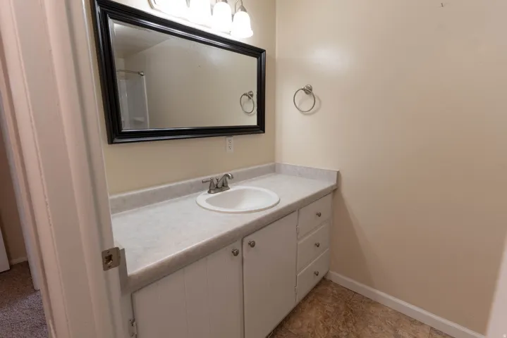Bathroom vanity featuring a white oval sink, chrome-finish faucet, and laminate countertop