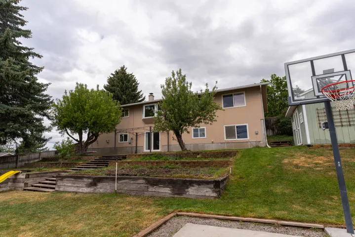 Multi-level backyard featuring wood-retaining walls and a basketball hoop, and storage shed !