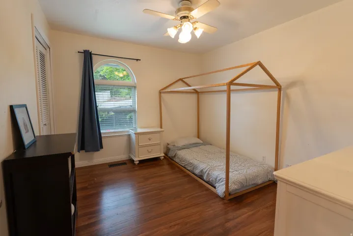 Bedroom with lots of light, a fun light fixture, and wood floors.