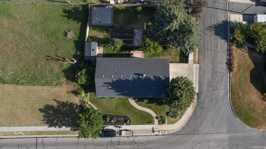Aerial perspective showcasing a property with a dark shingle roof and a concrete driveway