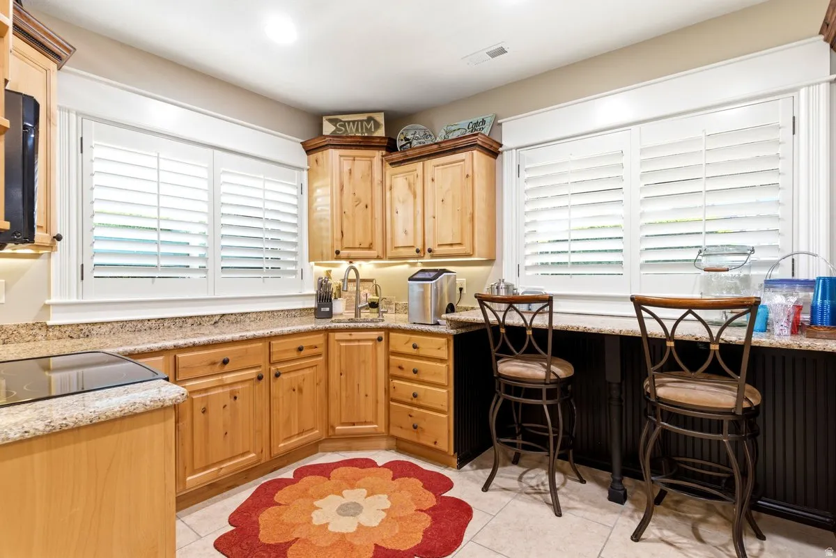 Corner kitchen featuring natural wood cabinetry with dark hardware, speckled countertops, and an integrated cooktop