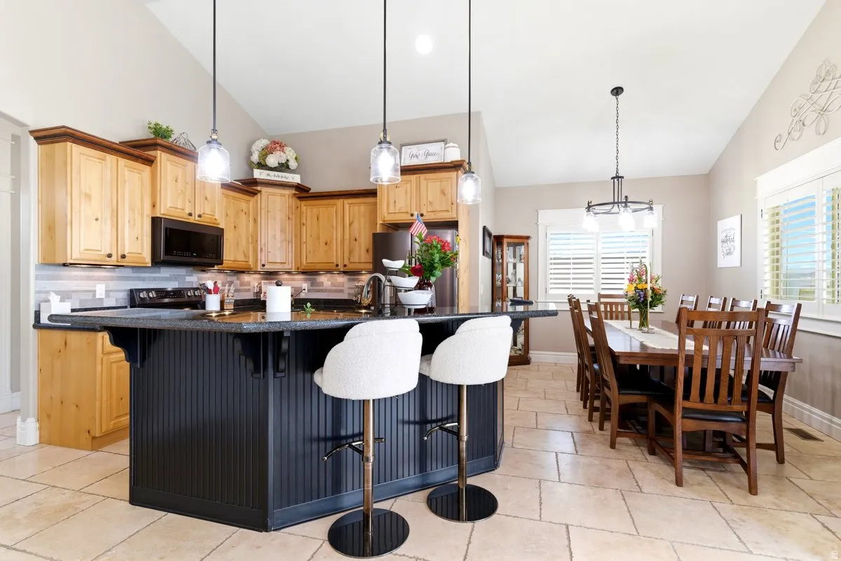 Spacious kitchen featuring natural wood cabinetry, dark countertops, a large island with beadboard paneling, and an integrated microwave