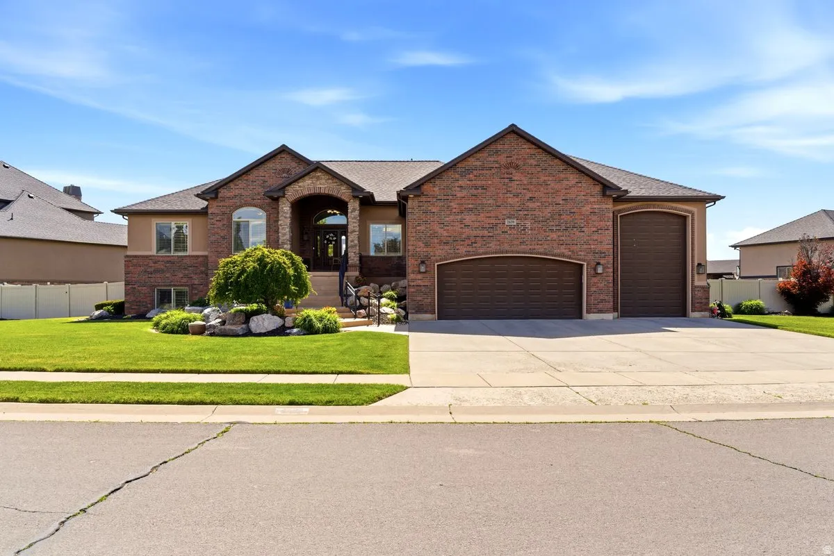 Traditional-style residence featuring a brick and stucco exterior, arched entry, and dark garage doors