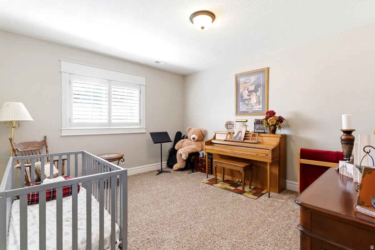 Carpeted room featuring a window with white plantation shutters, neutral painted walls, and white trim