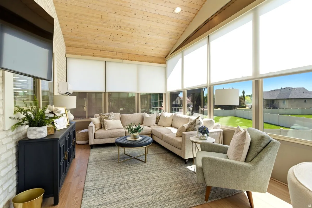 Sunroom featuring extensive window panels, vaulted wood-finish ceiling, and light wood-finish flooring
