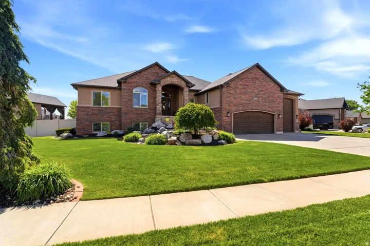 Brick and stucco residence featuring an arched portico entry with double doors, a two-car garage, and an additional single-car garage