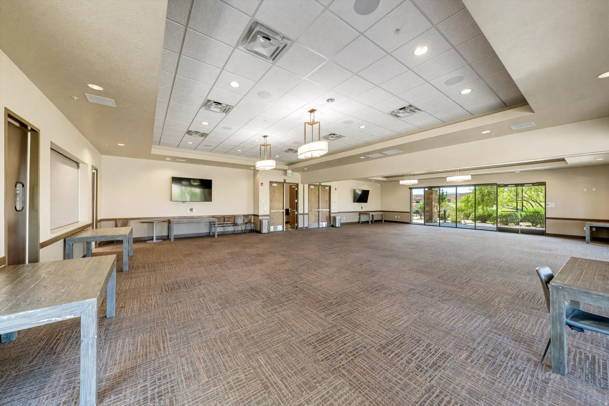 Expansive multi-purpose room featuring patterned carpet, recessed lighting, and large sliding glass doors