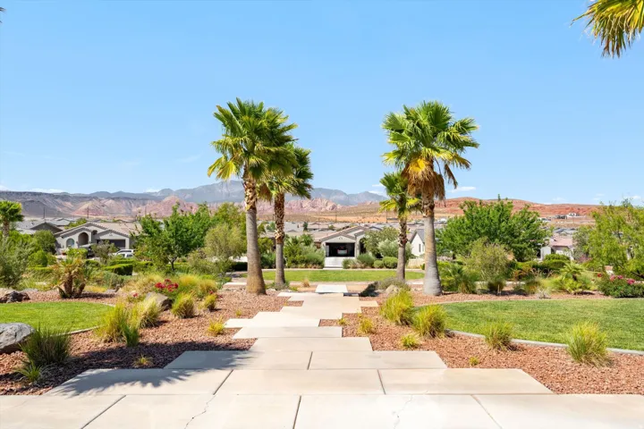 Manicured landscaping with palm trees, green lawns, and a stone-slab pathway