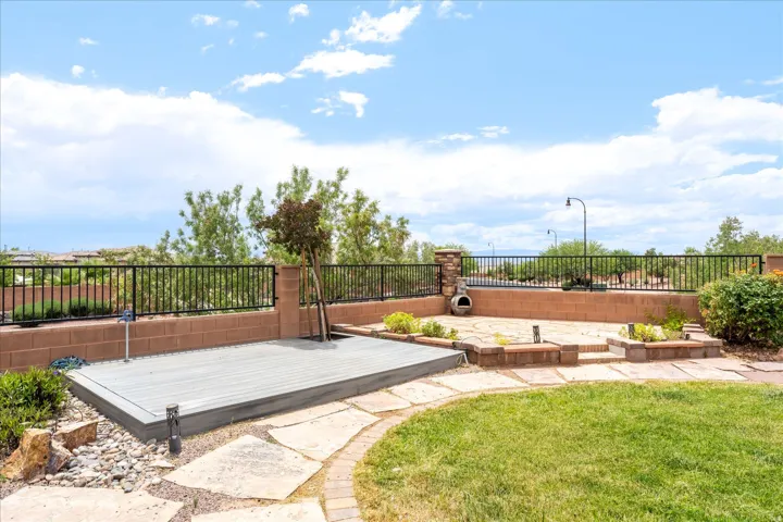 Multi-level backyard featuring a composite deck, flagstone patio, and a grass area