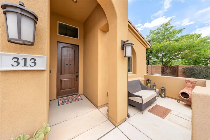 Covered front entry featuring a paneled wood door, transom window, and exterior sconce lighting