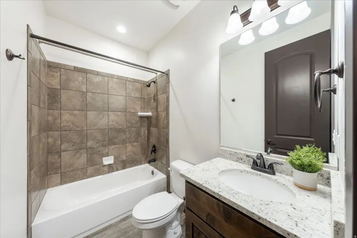 Full bathroom featuring a white tub with tiled shower surround, dark bronze fixtures, and a recessed ceiling light