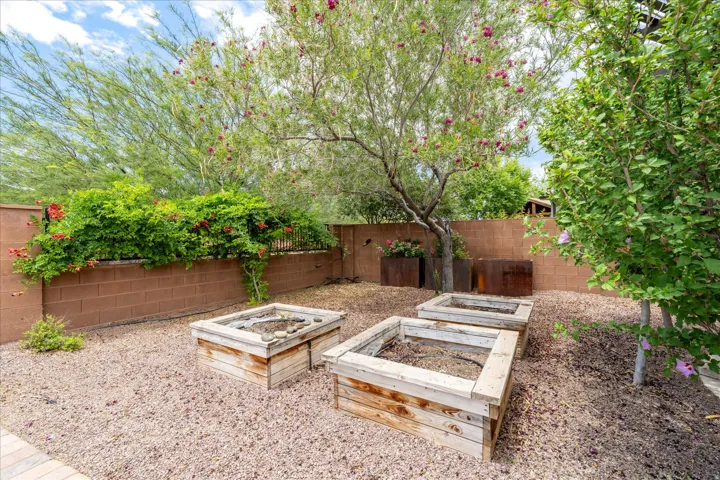 Low-maintenance backyard featuring gravel landscaping, a solid block wall, and mature trees