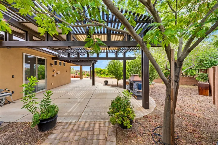 Expansive patio featuring a large pergola, smooth concrete surfacing, and brick paver accents